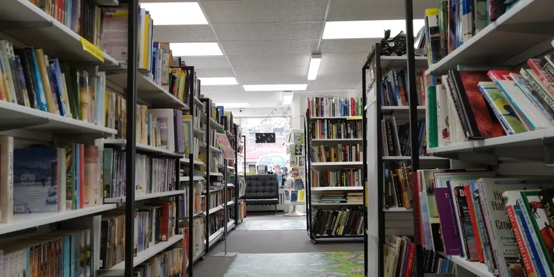 The inside of the shop: a long aisle of floor-to-ceiling shelves running to the window at the front, every shelf full of books.